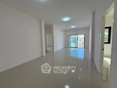 Spacious empty living room with glossy tiled floors and large windows leading to a balcony.