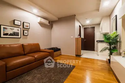 Modern living room with wooden flooring, brown leather sofa, and stylish decor in a cozy apartment.
