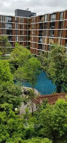 Modern apartment complex with lush greenery and a serene pool view.