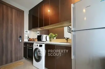 Modern kitchen with sleek cabinets, washing machine, and fridge in compact layout.