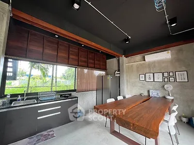 Modern kitchen with sleek design and wooden dining table, featuring open layout and natural light.