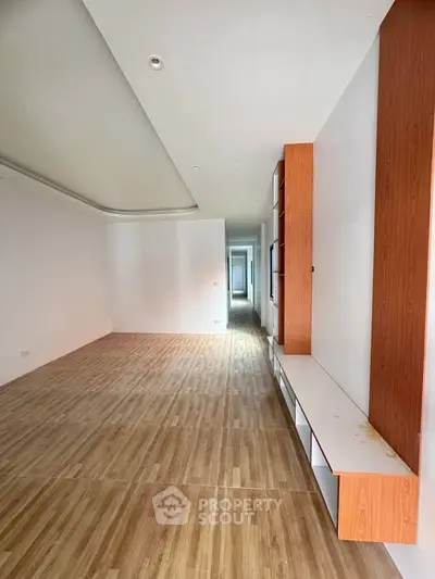 Spacious modern living room with wooden flooring and built-in shelving