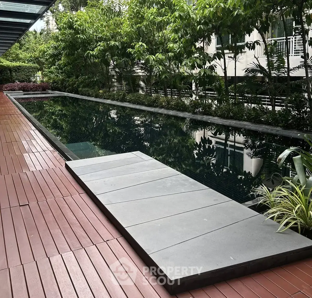 Luxurious outdoor pool surrounded by lush greenery in a modern residential complex.
