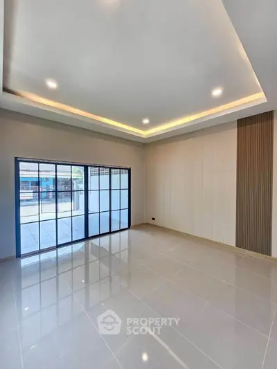Spacious modern living room with large windows and elegant ceiling lights.