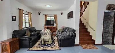 Spacious living room with elegant leather sofas and wooden staircase