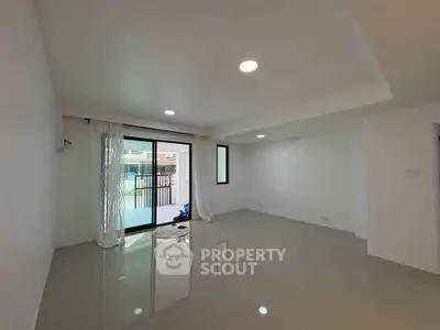 Spacious living room with large windows and balcony access, featuring sleek tile flooring and modern lighting.