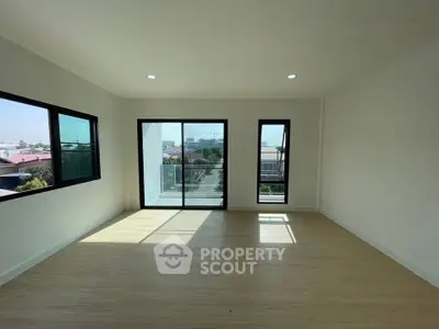 Spacious modern living room with large windows and balcony access, offering abundant natural light and city views.