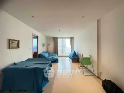 Spacious living room with covered furniture and city view