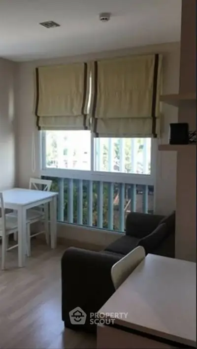 Cozy living room with natural light, featuring a small dining area and comfortable seating.