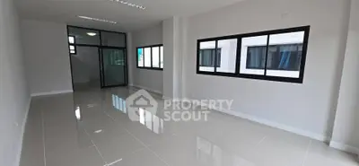 Spacious modern living room with large windows and glossy tiled floors.