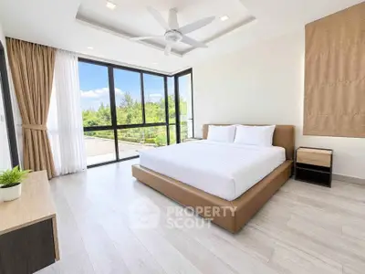 Spacious bedroom with large windows and garden view, featuring modern decor and natural light.