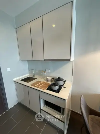 Modern compact kitchen with sleek cabinetry and built-in appliances in a stylish apartment.