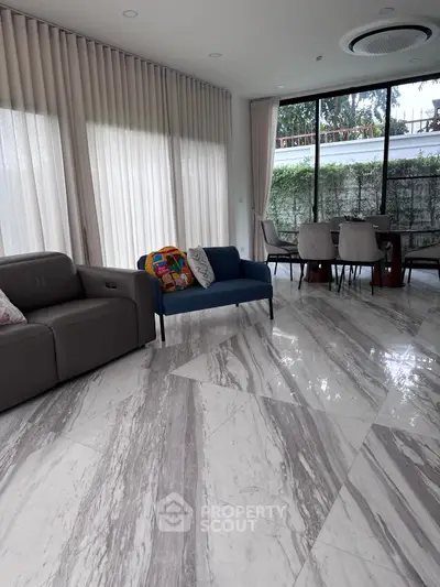 Luxurious living room with marble flooring and elegant dining area, featuring modern furniture and large windows.