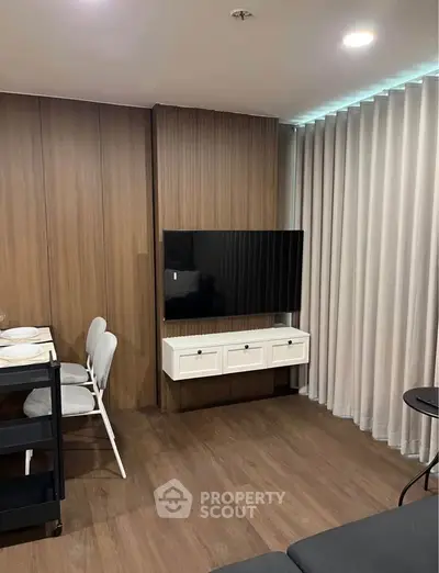 Modern living room with sleek wooden paneling and mounted TV, featuring elegant dining setup.