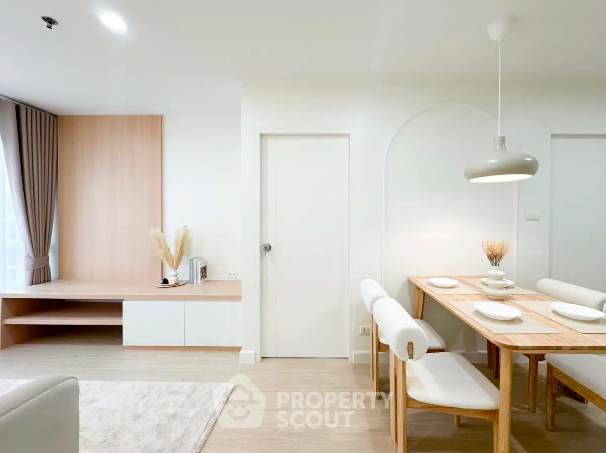 Modern dining area with wooden table and chairs, minimalist decor, and natural light.