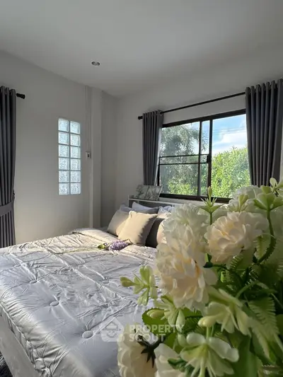 Cozy bedroom with large window and elegant decor, offering a serene and inviting atmosphere.