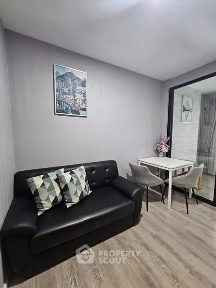 Modern living room with sleek black sofa and dining area in stylish apartment.