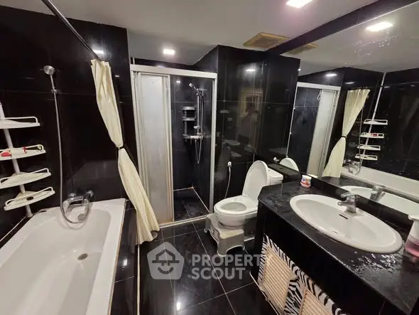Luxurious black-tiled bathroom with bathtub and modern fixtures