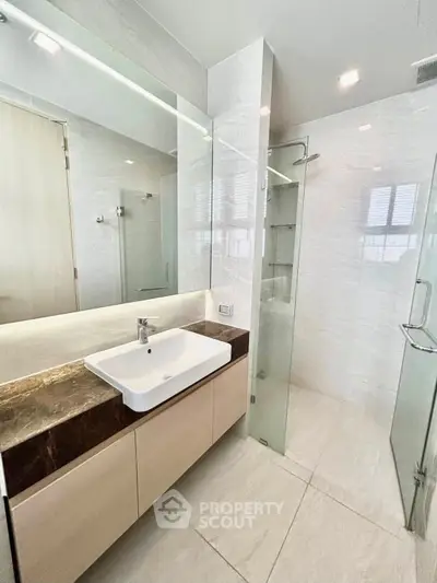 Modern bathroom with sleek design, featuring a glass shower and elegant vanity.