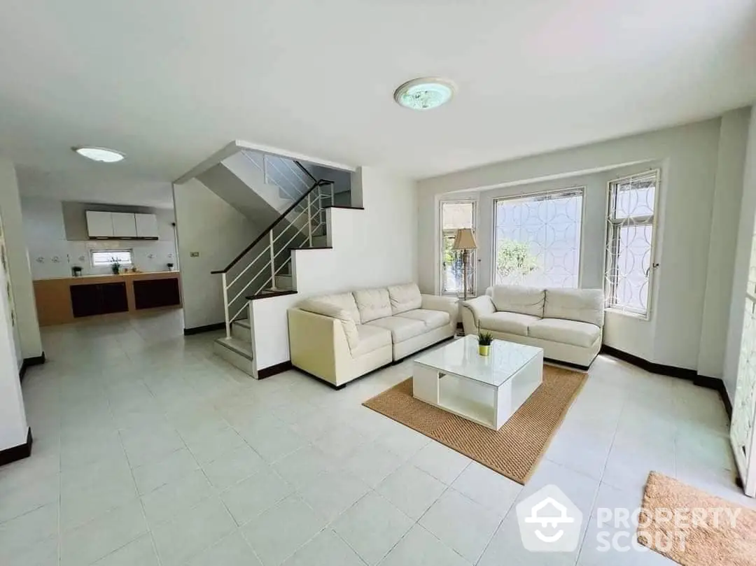 Bright and airy open-plan living space with modern staircase, large windows, and a seamless transition to the kitchen area, perfect for entertaining and comfortable living.