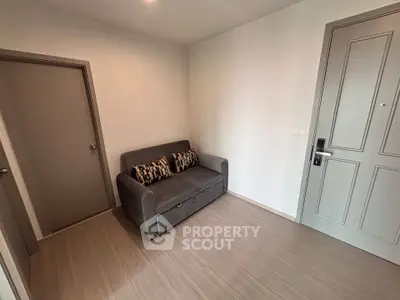 Cozy small living room with a modern gray sofa and wooden flooring, perfect for compact spaces.