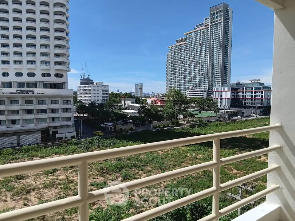 Stunning urban view from a balcony overlooking modern high-rise buildings and lush greenery.