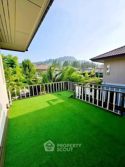 Spacious balcony with artificial grass and scenic mountain view in a modern home.