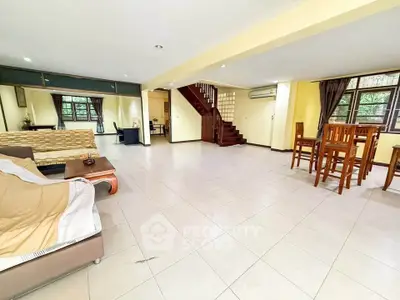 Spacious open-plan living room with dining area and staircase, ideal for family gatherings.