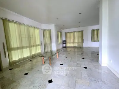 Spacious living room with marble flooring and large windows, perfect for natural light.