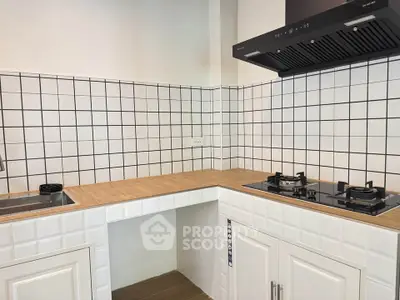 Modern kitchen with gas stove and tiled backsplash, featuring sleek wooden countertops.