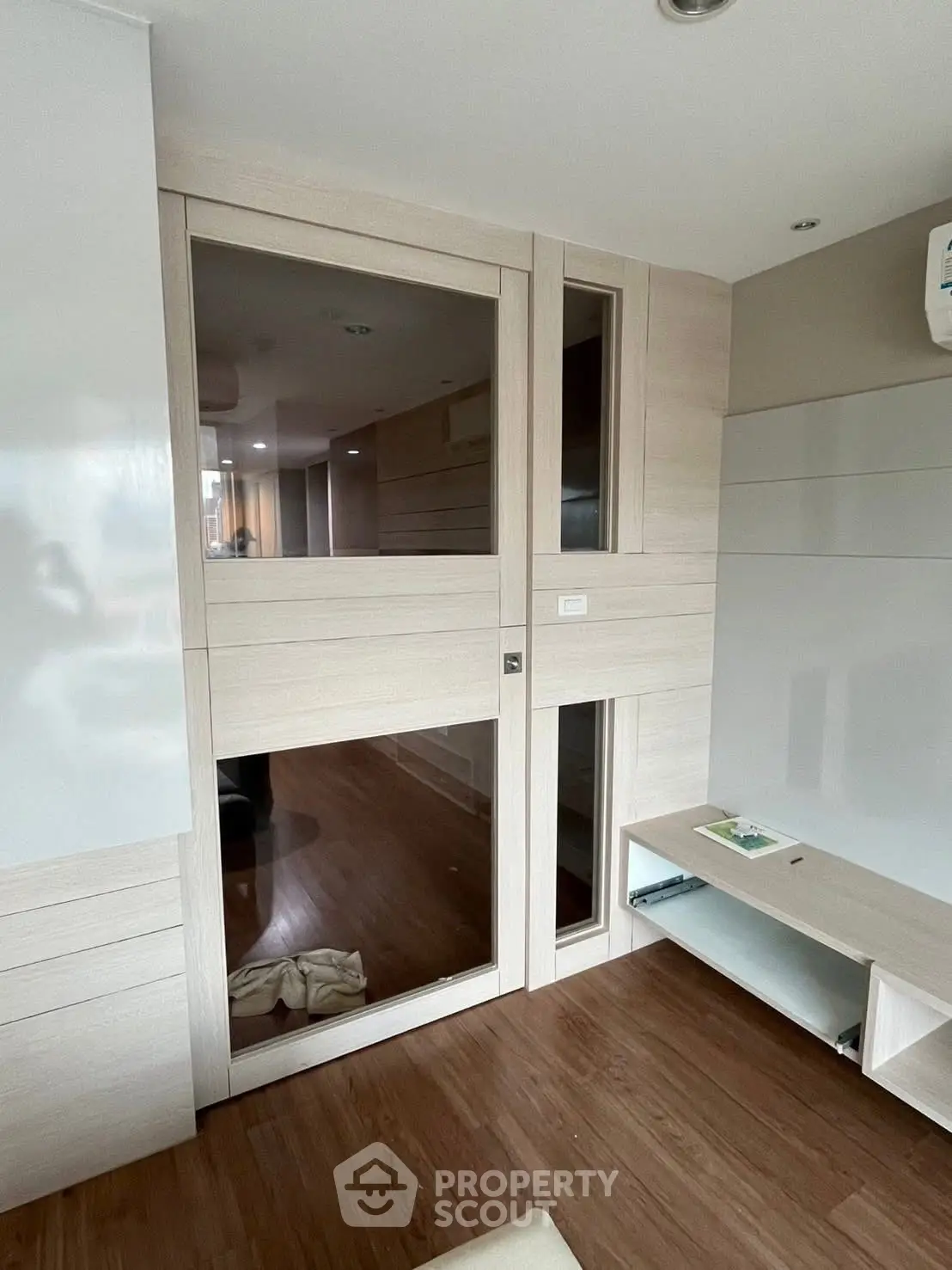 Modern interior with wooden flooring and built-in storage, featuring sleek design and neutral tones.