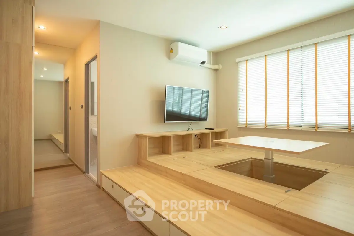 Modern minimalist living room with raised wooden platform and wall-mounted TV