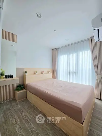 Modern bedroom with natural light, wooden flooring, and minimalist decor in a stylish apartment.
