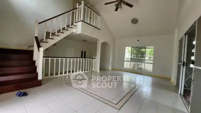 Spacious open-plan living room with high ceiling and staircase