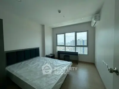 Spacious bedroom with large windows offering stunning city views in modern apartment.