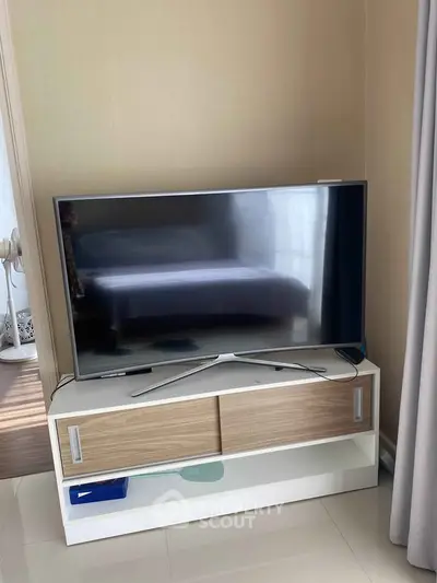 Modern living room with sleek TV on stylish stand, perfect for cozy entertainment nights.