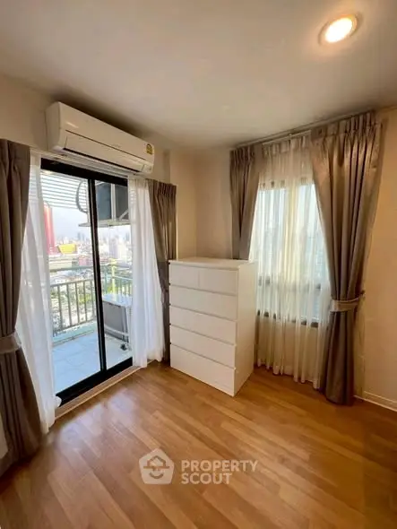 Bright corner unit with balcony and city view, featuring hardwood floors and modern air conditioning.
