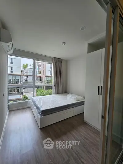 Modern bedroom with large window and built-in wardrobe in urban apartment