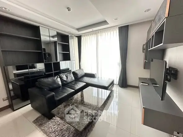 Modern living room with sleek black furniture and large windows for natural light.