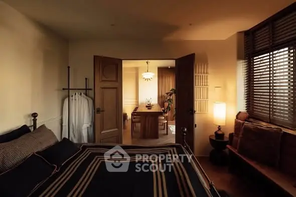 Cozy bedroom with stylish decor and view into a warm dining area