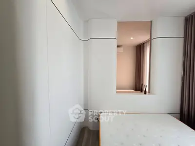 Modern minimalist bedroom with sleek white walls and large window for natural light.