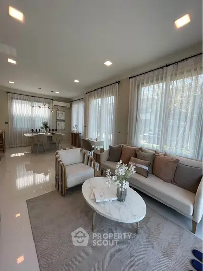 Elegant living room with modern furniture and large windows in a bright, airy space.