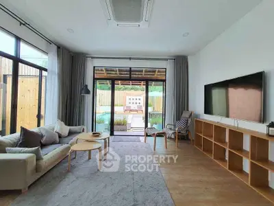 Spacious living room with modern decor and pool view, featuring large windows and cozy seating area.