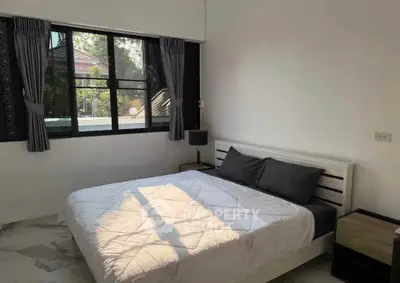 Cozy bedroom with large window and modern decor, perfect for relaxation.