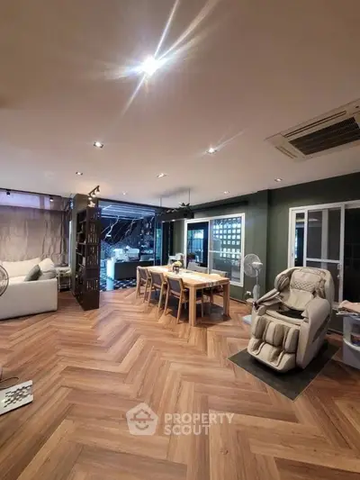 Spacious living room with modern decor and open layout, featuring a dining area and massage chair.