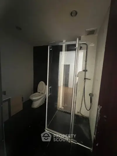 Modern bathroom with glass shower enclosure and sleek black tiles.