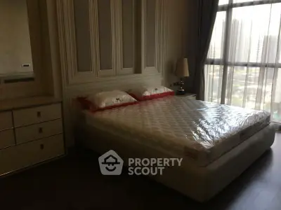 Luxurious bedroom with large window offering stunning city views, featuring elegant decor and a comfortable bed.