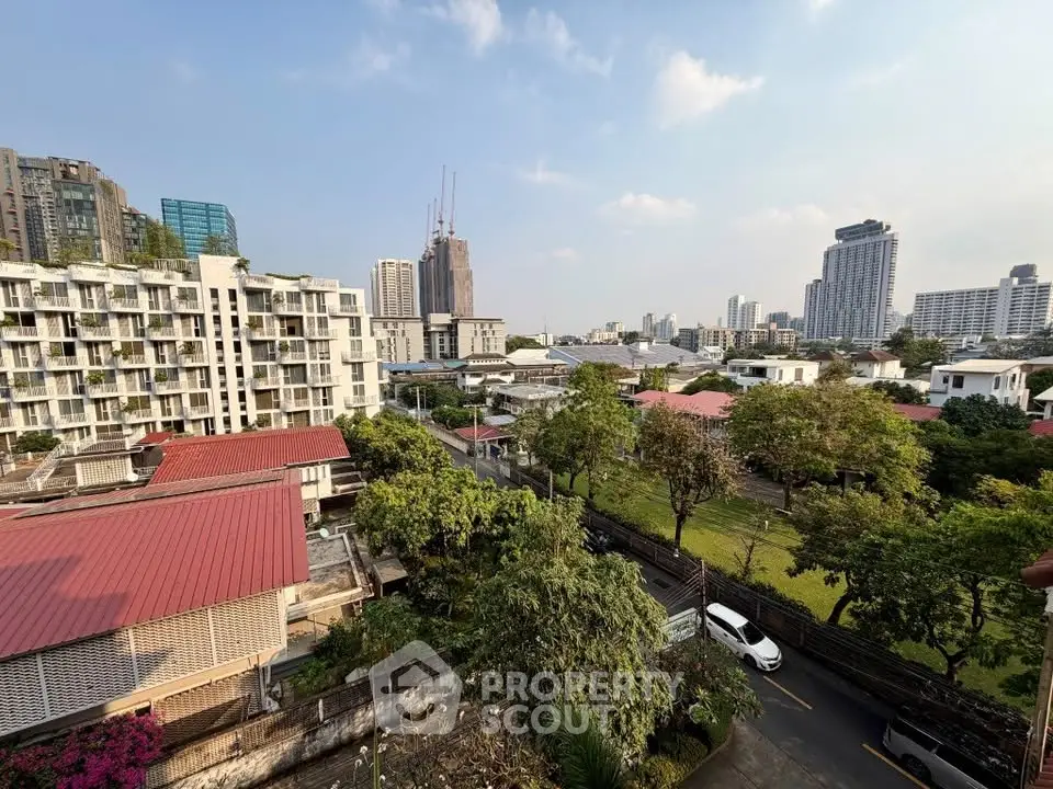 Stunning cityscape view from a high-rise building, showcasing urban skyline and lush greenery.