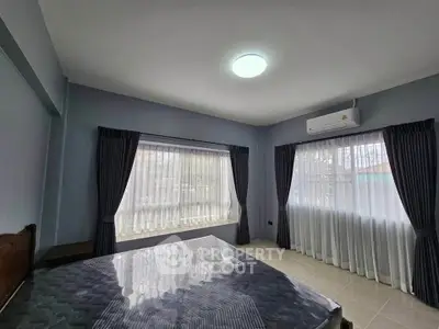 Spacious bedroom with large windows and natural light, featuring modern air conditioning.