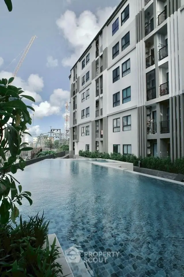 Modern apartment building with a luxurious outdoor pool and city view.